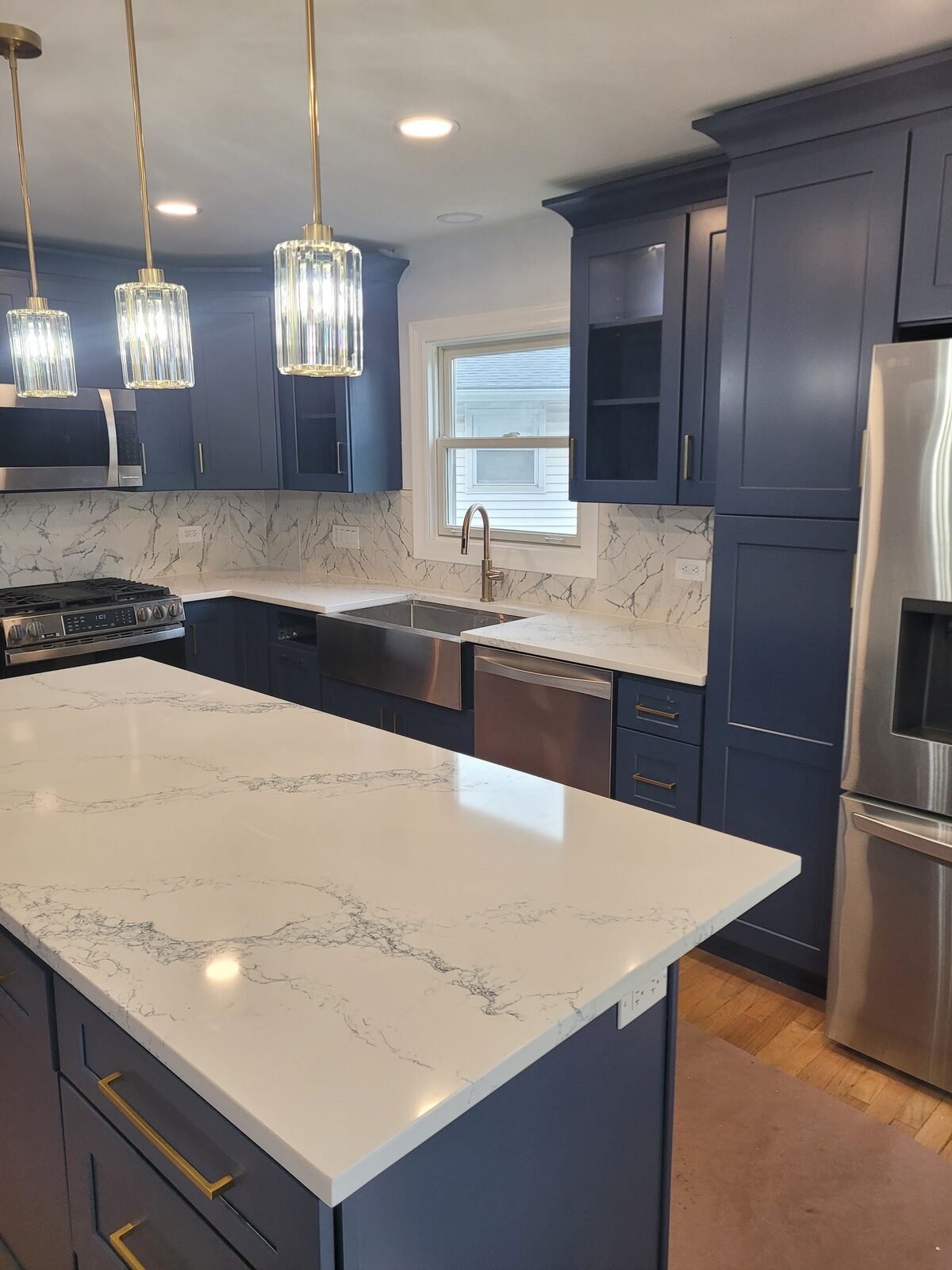 Navy kitchen island with quartz counter and pendant lights
