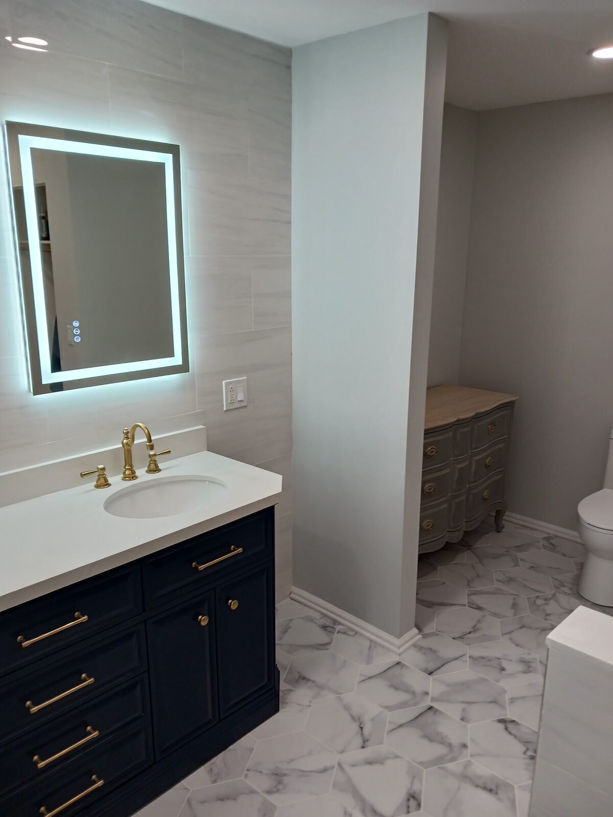 Navy bathroom vanity with backlit mirror and brass faucet